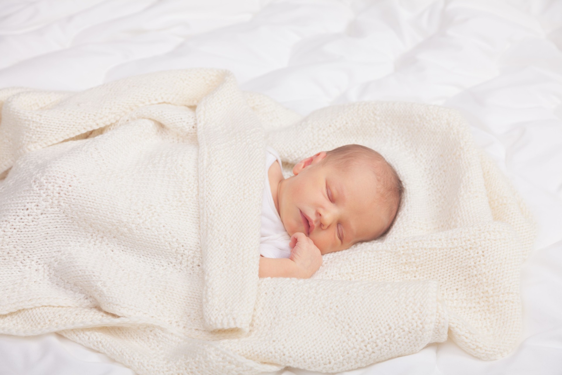 Newborn Baby Asleep Wrapped in Knit Blanket